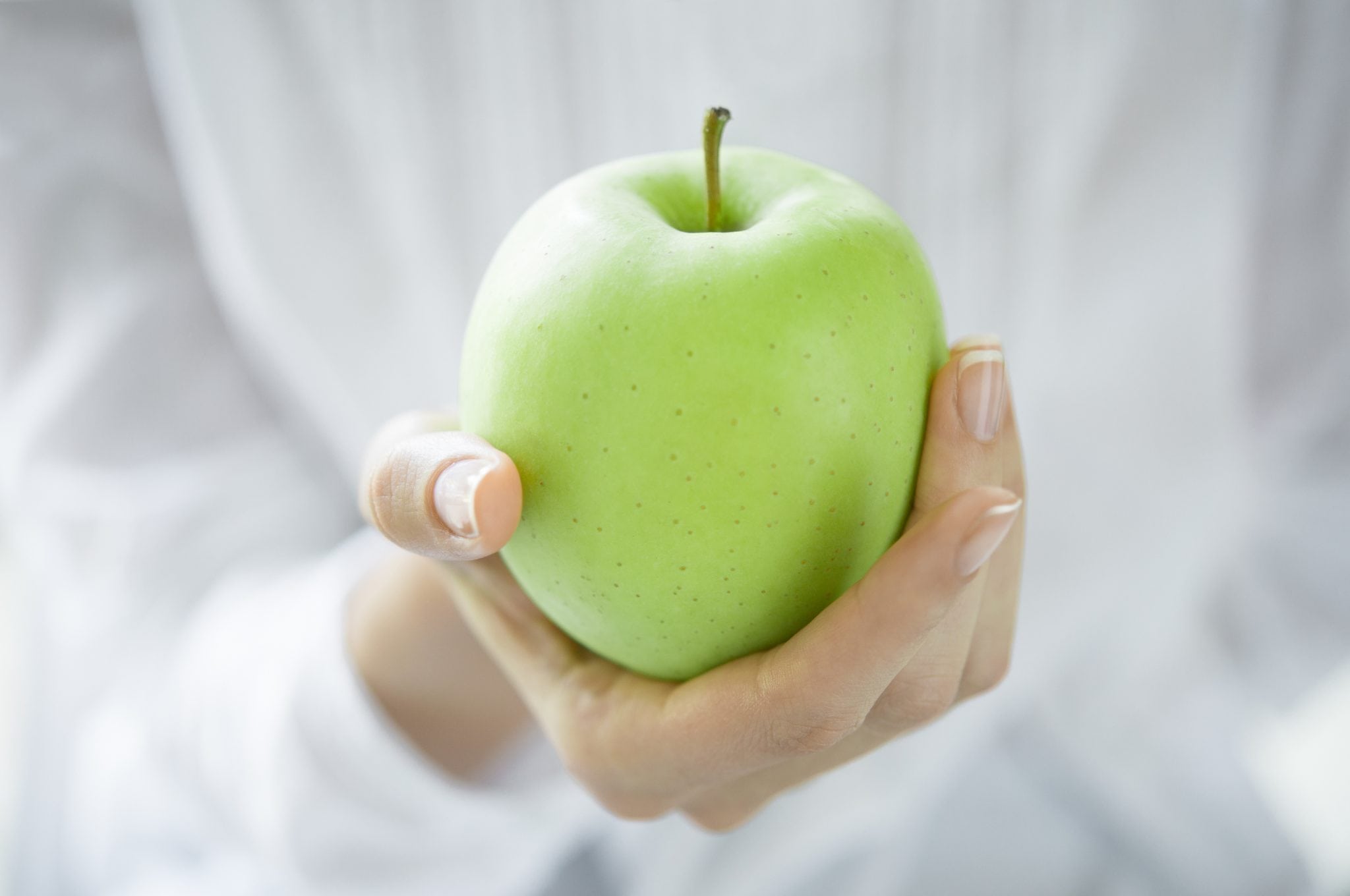 Closeup shot of a woman holding green apple.