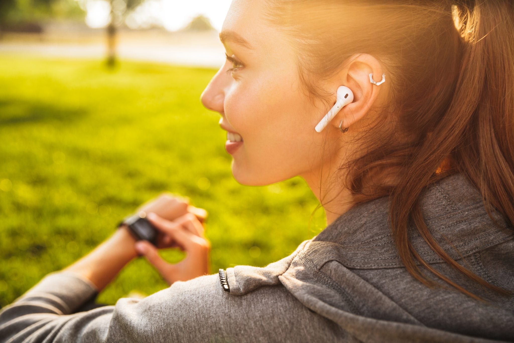 female runner wearing earbuds and checking smartphone