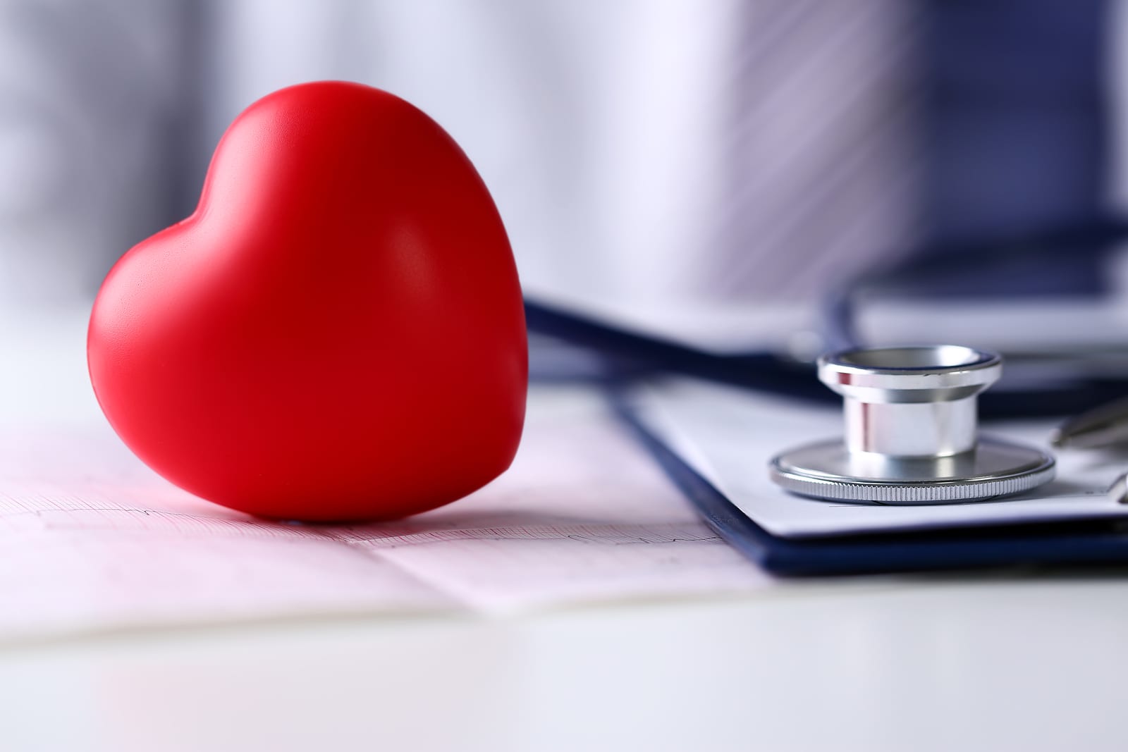 Medical stethoscope head and red toy heart lying on cardiogram chart closeup. Cardio therapeutist pulse graph cardiac physical heart rate measure arrhythmia 911 er and resuscitation concept