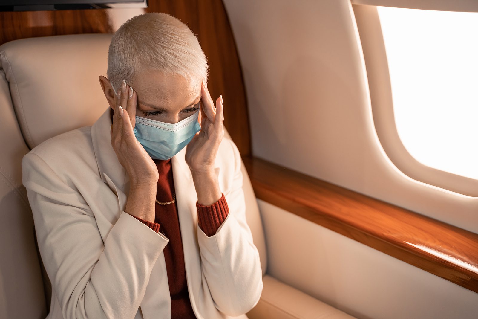 Older woman suffering from airplane ear ears pop when flying